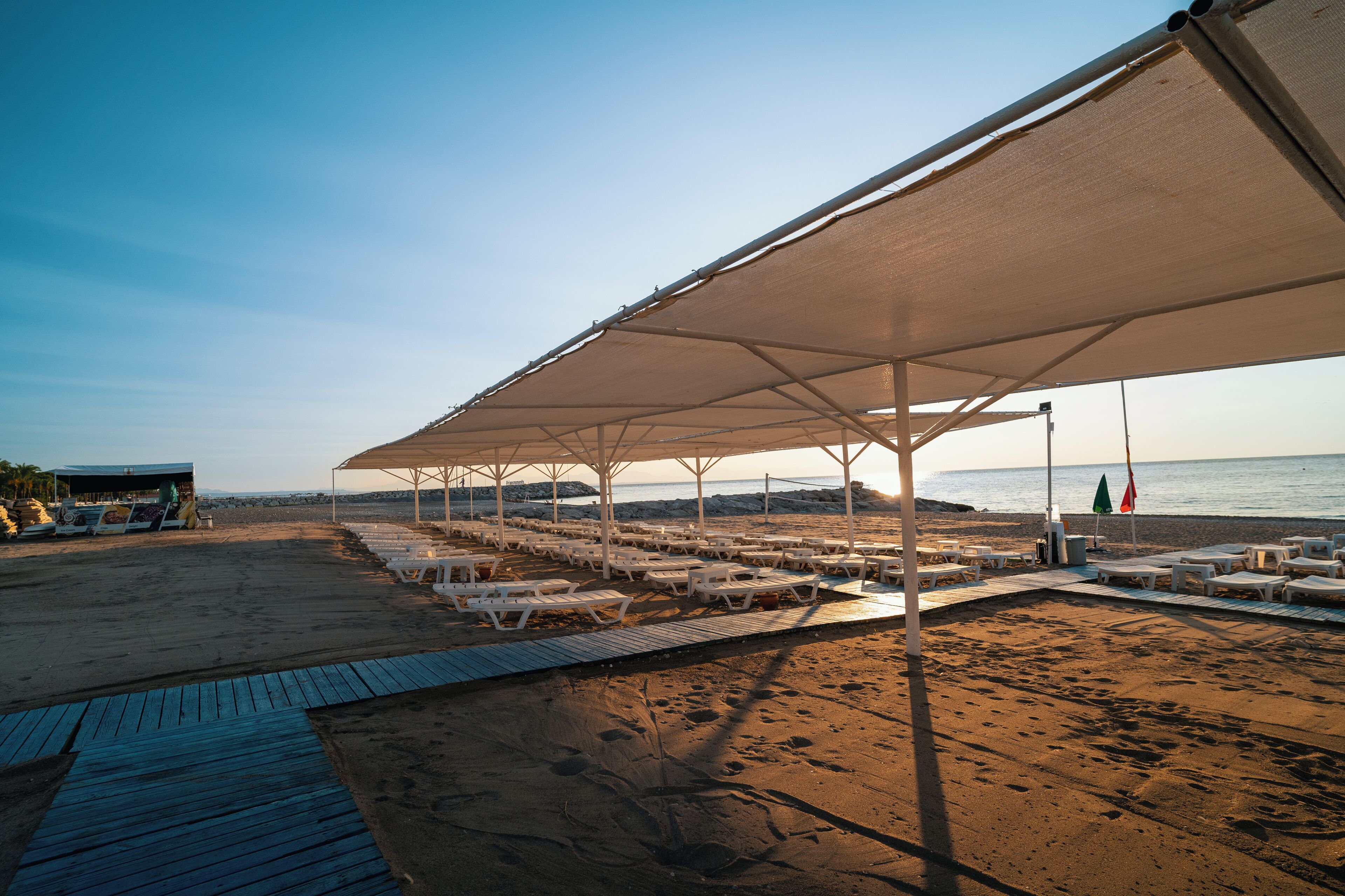Una zona de playa con un área de estar cubierta y una terraza de madera.