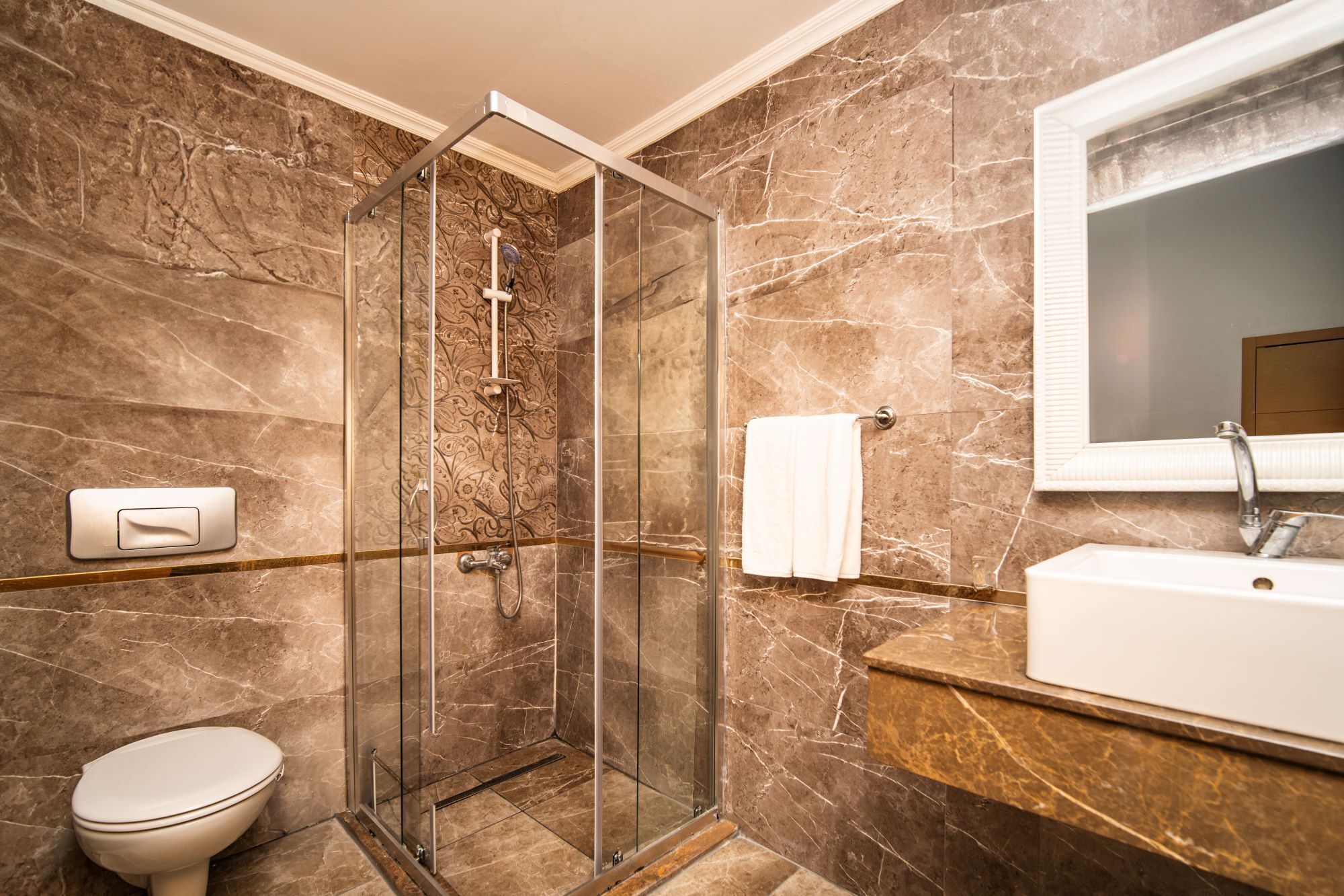 A modern bathroom with a glass-enclosed shower, a toilet, and a sink with a mirror.