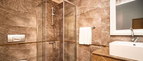 A modern bathroom with a glass-enclosed shower, a toilet, and a sink with a mirror.