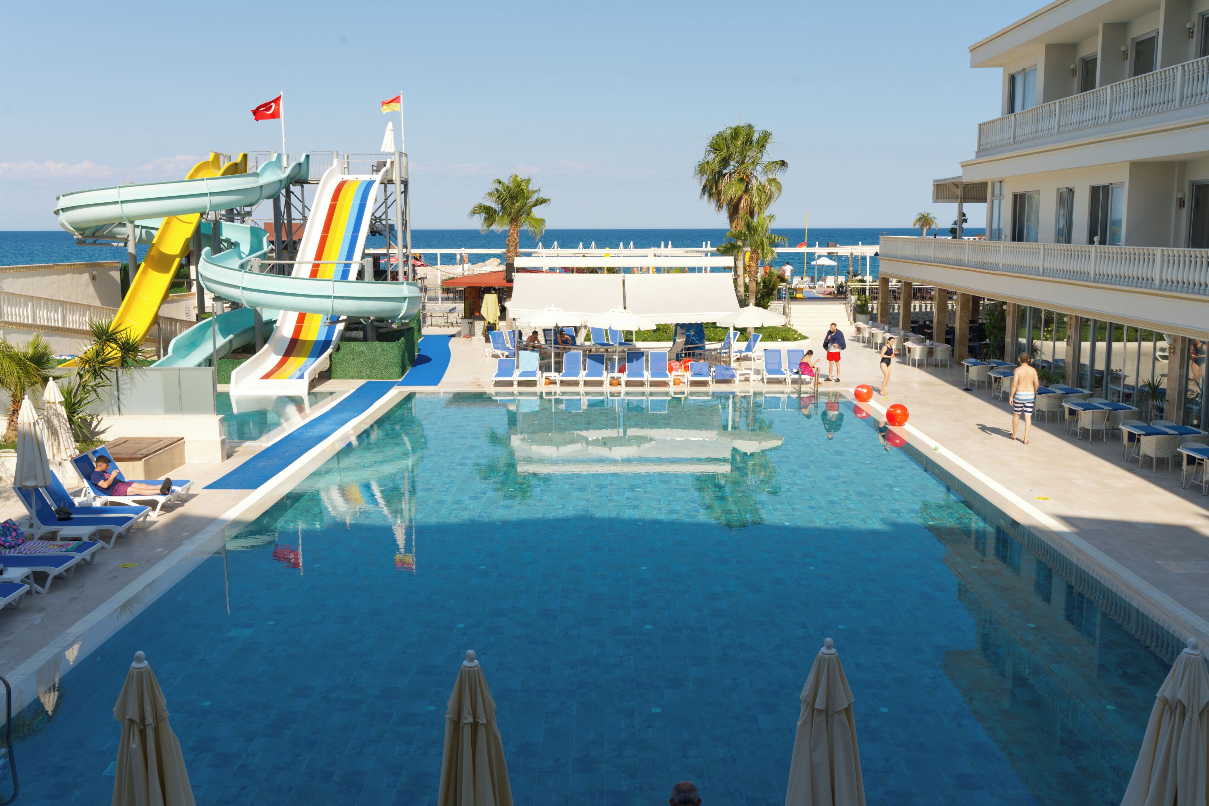 Un espace piscine doté de toboggans, de chaises longues et de parasols.