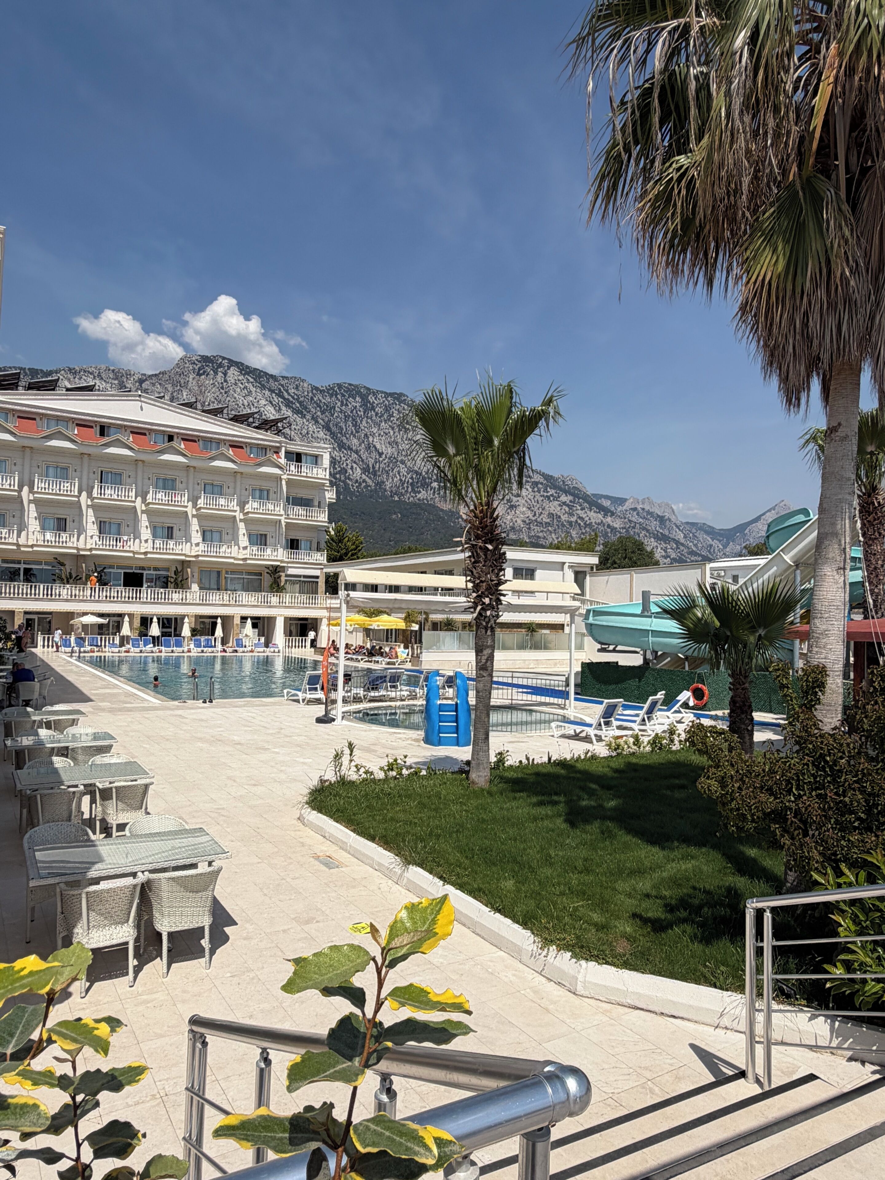 A hotel with a pool, outdoor seating, and a mountain backdrop.