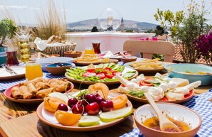 Una mesa dispuesta con diversos platos, incluyendo frutas, verduras y queso, con una vista panorámica al fondo.
