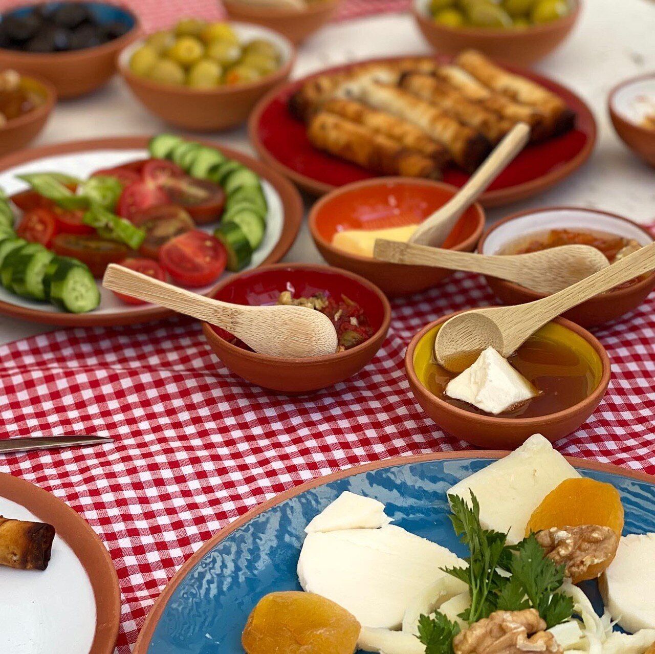 Una mesa con diversos platos, entre ellos ensaladas, quesos y carnes, que sugiere un ambiente para comer.