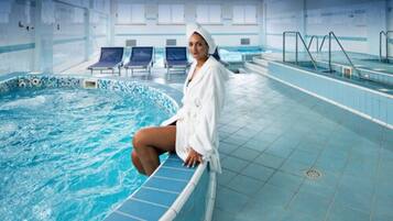 A person sitting by a pool with a tiled floor and a view of the pool area.