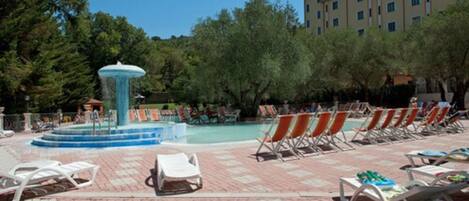 A pool area with lounge chairs and a fountain.