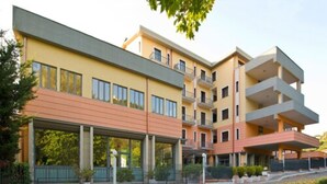 Un hotel a più piani con tetto piatto, balconi e un'area d'ingresso coperta.