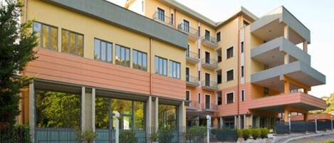 A multi-story hotel with a flat roof, balconies, and a covered entrance area.