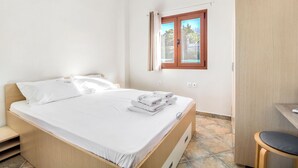 A bedroom with a bed, a wooden wardrobe, a small desk, and a window with curtains. - Sea View Villas (Sithonia)