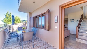 A balcony with a table and chairs, a view of the landscape, and a staircase leading to the interior. - Sea View Villas (Sithonia)