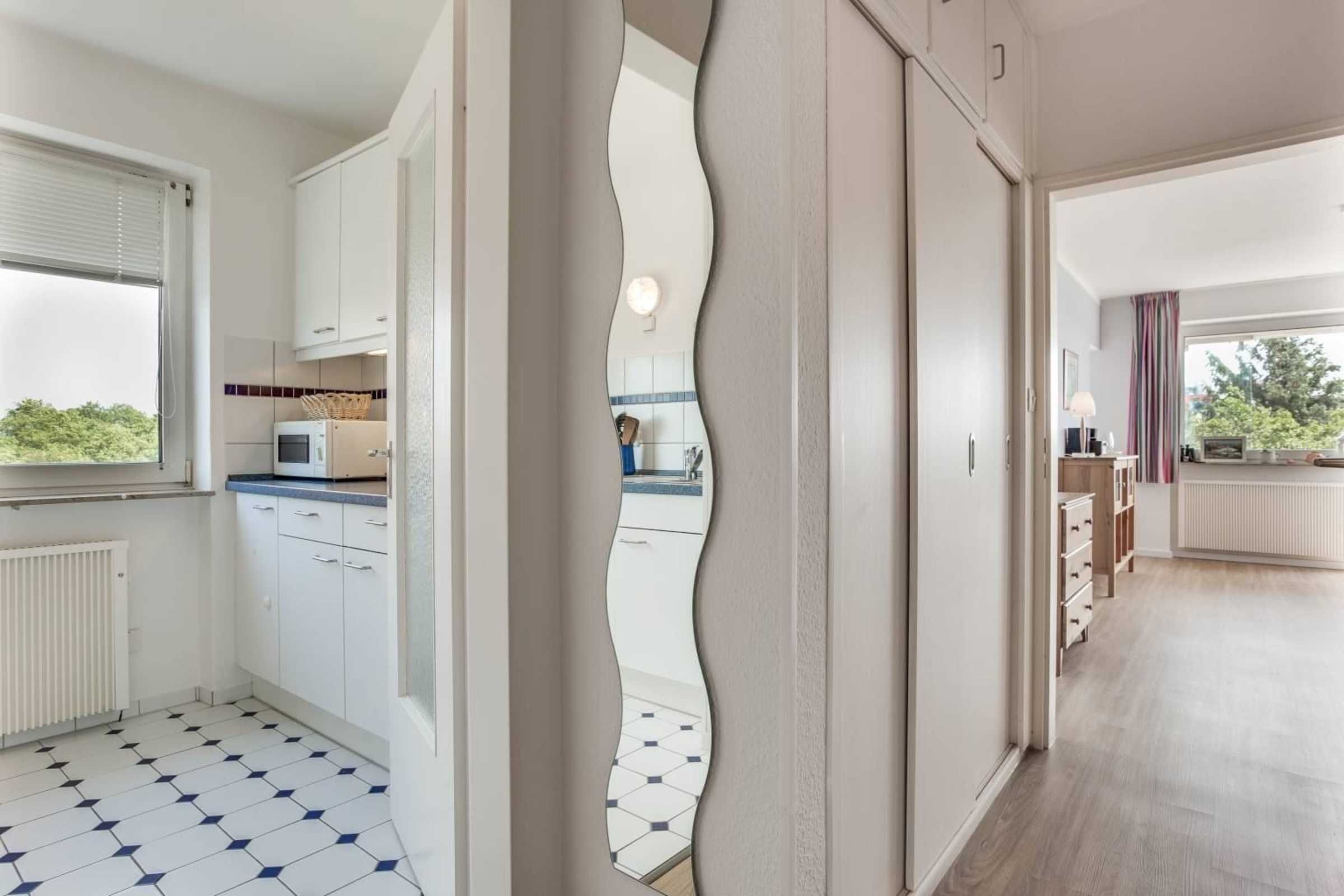 A modern kitchen with white cabinets, a microwave, and a tiled floor.