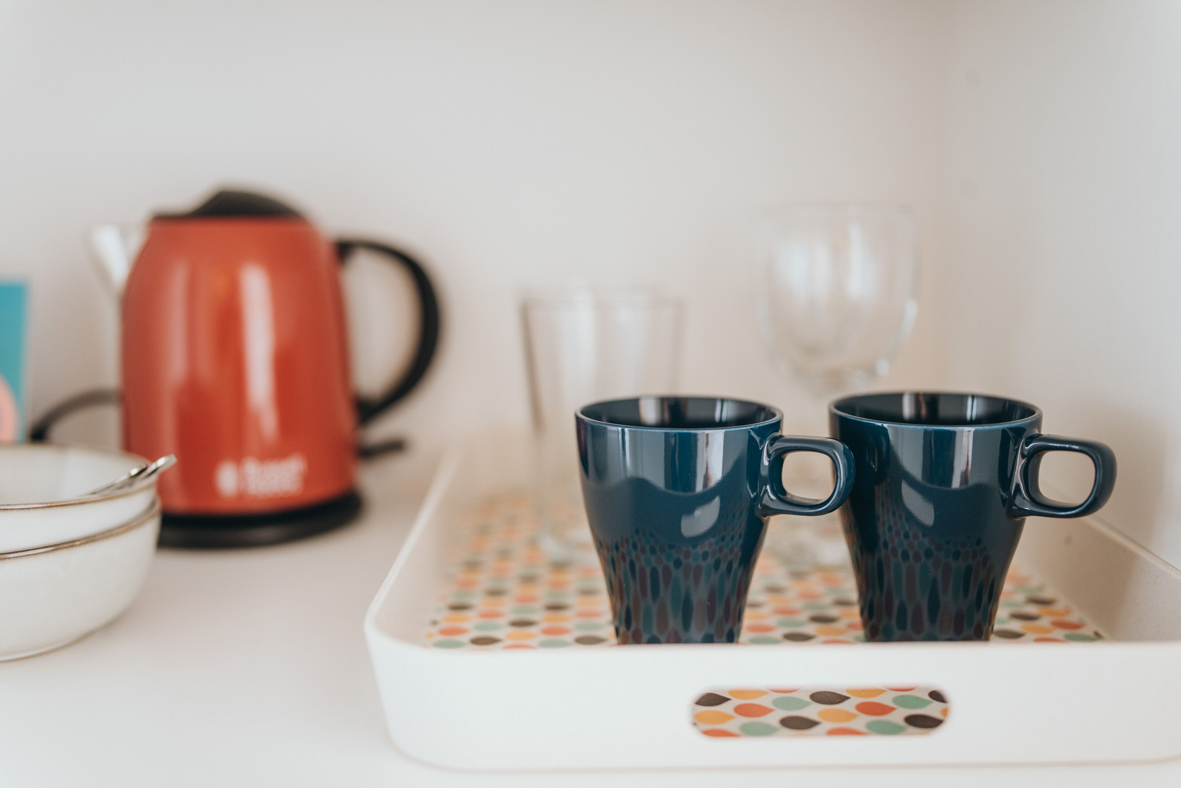 Een aanrecht met een koffiezetapparaat, twee mokken en een glas.