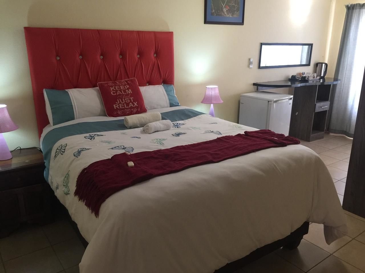 Habitación de hotel con cama, escritorio, silla, lámpara y ventana.