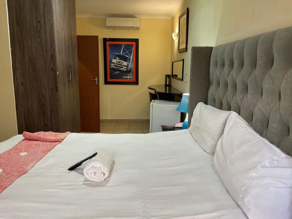 A hotel room with a bed, a desk, a chair, and a door.