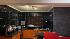 A modern kitchen with black marble tiles, wooden cabinets, and a red and white chair.