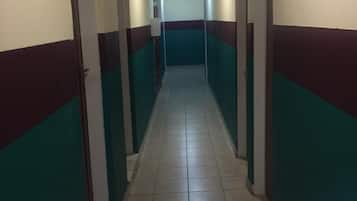 A long, narrow hallway with tiled flooring and walls painted in alternating stripes of teal and maroon.