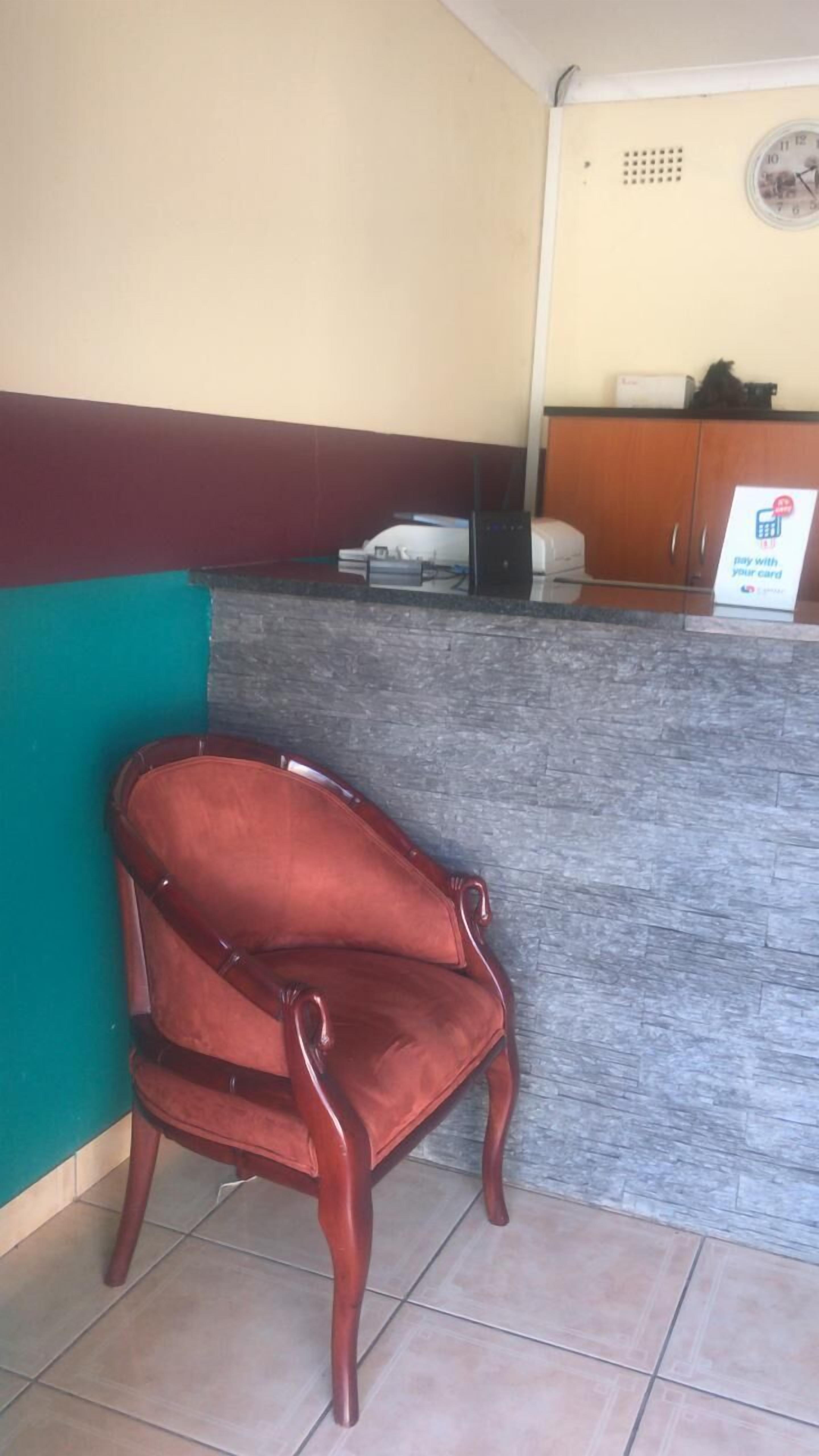 A reception area with a wooden chair, a counter, and a sign indicating payment with a card.