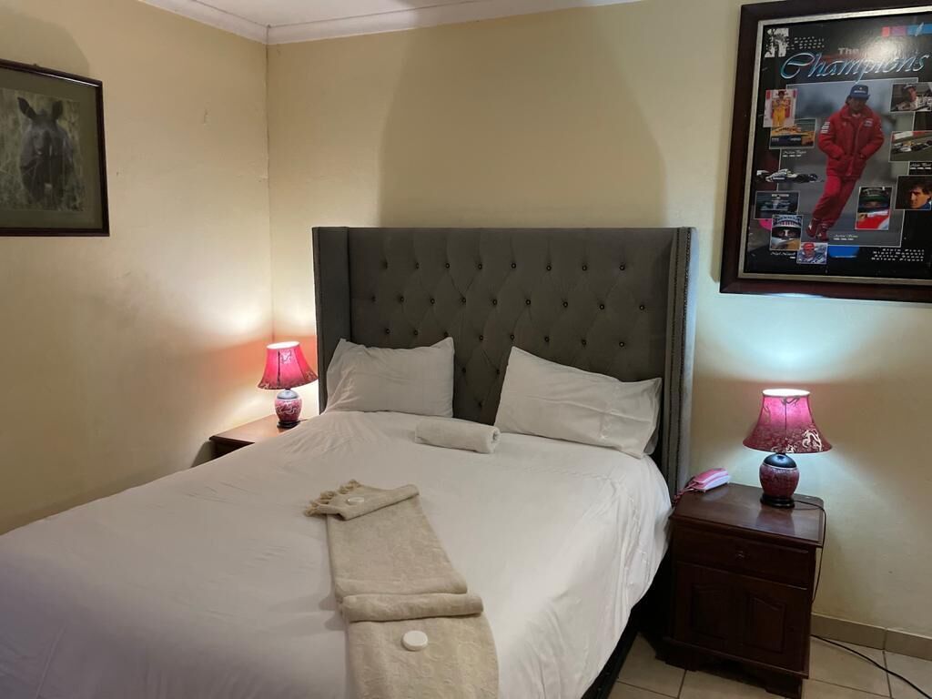 A neatly made bed with white linens, a tufted headboard, and two bedside lamps.