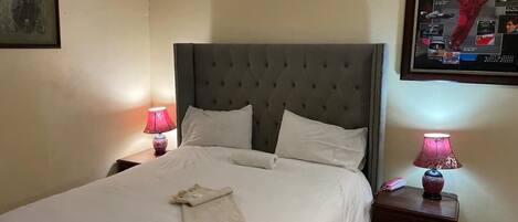 A neatly made bed with white linens, a tufted headboard, and two bedside lamps.