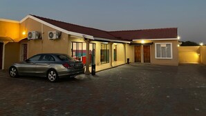 A building with a car parked in front, air conditioning units, and a tiled roof.
