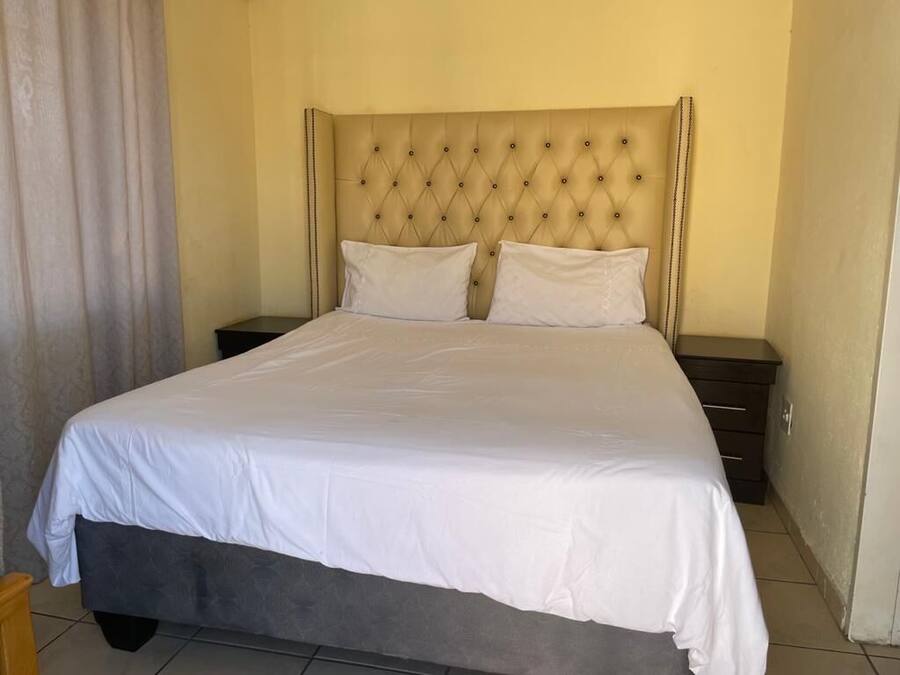 Una cama bien tendida con cabecera capitonada en una habitación de hotel.
