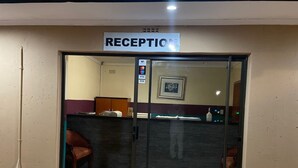 A reception area with a sign above the door, a reception desk, and a chair.