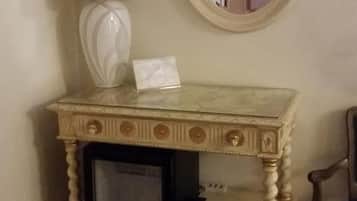 Uma pequena mesa de madeira ricamente decorada, com uma luminária e um espelho.