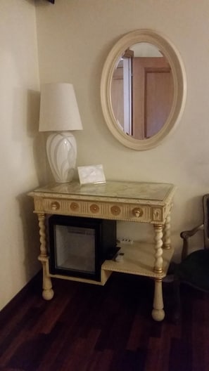 Un petit bureau en bois, élégamment décoré, avec une lampe et un miroir.