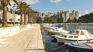 A marina with several boats docked, a paved walkway, and a row of palm trees. - Cozy apartment in Ploce with WiFi (Ploce)