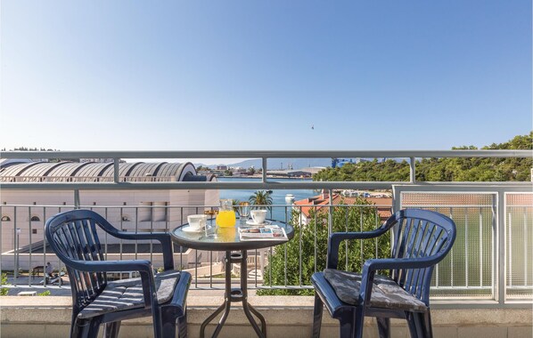 Een balkon met twee stoelen en een tafel, met uitzicht op een jachthaven en gebouwen.