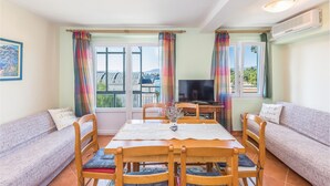 A dining area with a table and chairs, a sofa, a TV, and large windows with curtains. - Cozy apartment in Ploce with WiFi (Ploce)