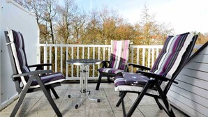 A patio with two chairs and a small table, surrounded by a white fence. - Apartment 8 Strandstar (ID 118) (Sankt Peter-Ording)