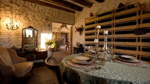 Un comedor rústico con pared de ladrillo, botellero de madera y una mesa dispuesta para dos personas.