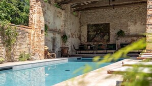 Un área de piscina con pared de ladrillo rústico, sillones de descanso y un cuadro.