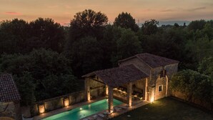 Una villa con piscina, zona de estar exterior y fachada de piedra.