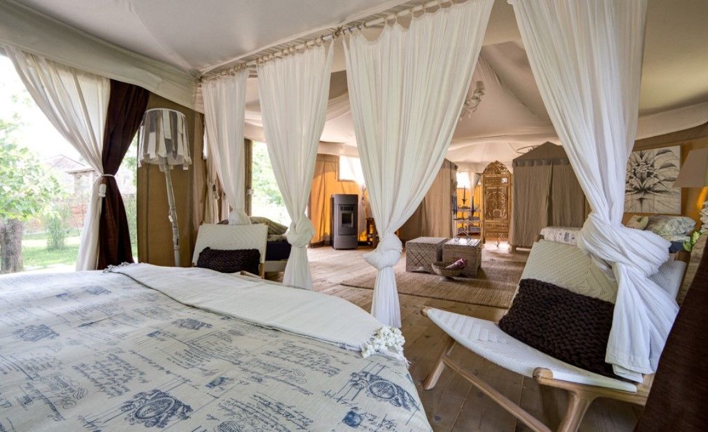 A bedroom with a large bed, a chair, and a canopy bed.