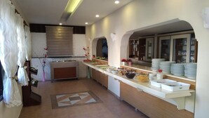 Uma cozinha moderna com um balcão comprido, diversos alimentos e piso revestido de azulejos.
