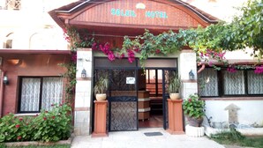A entrada do Hotel Soleil, com fachada de madeira, uma placa acima da entrada e plantas em vasos ao redor.
