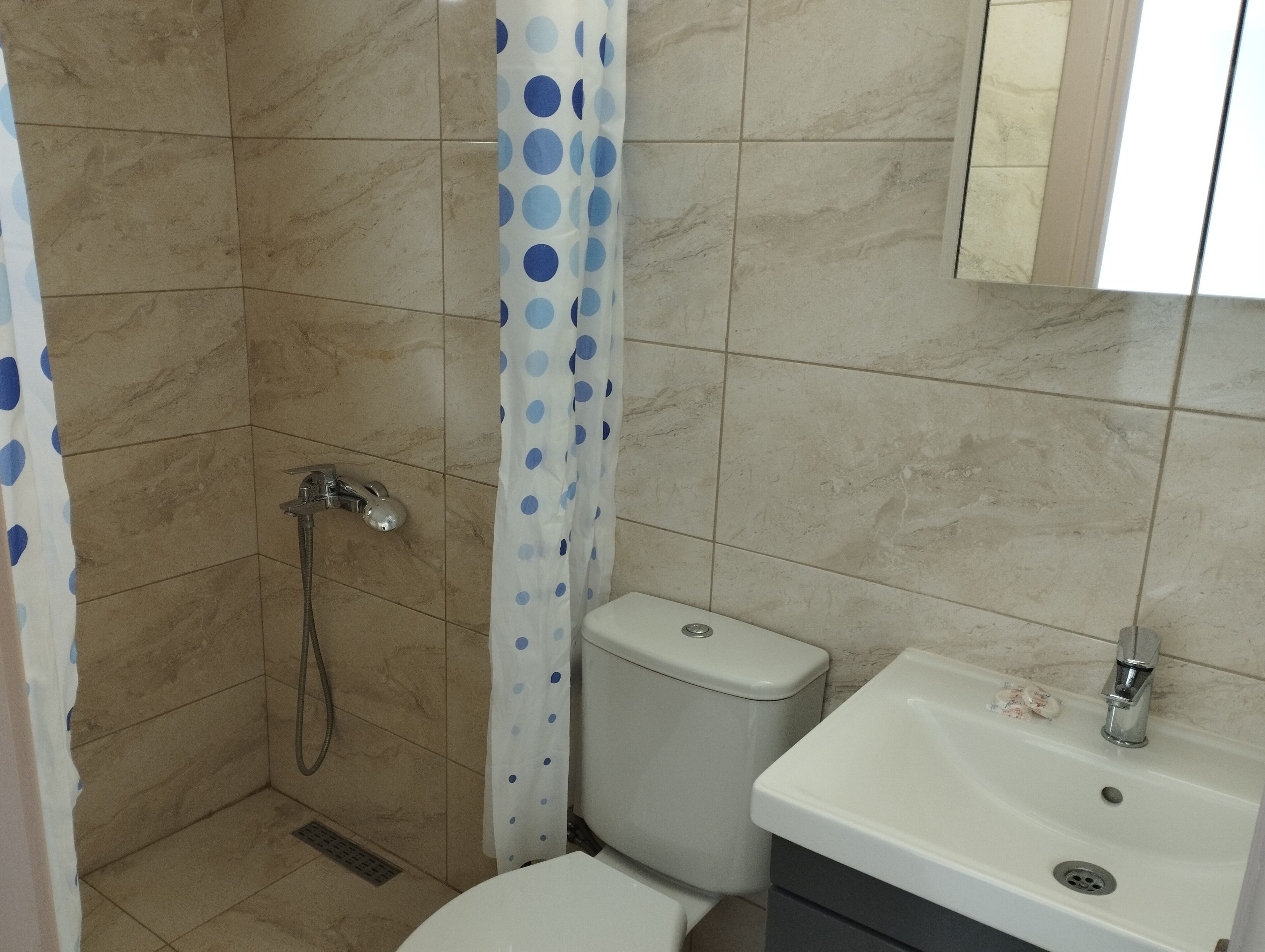 A bathroom with a shower, toilet, and sink.