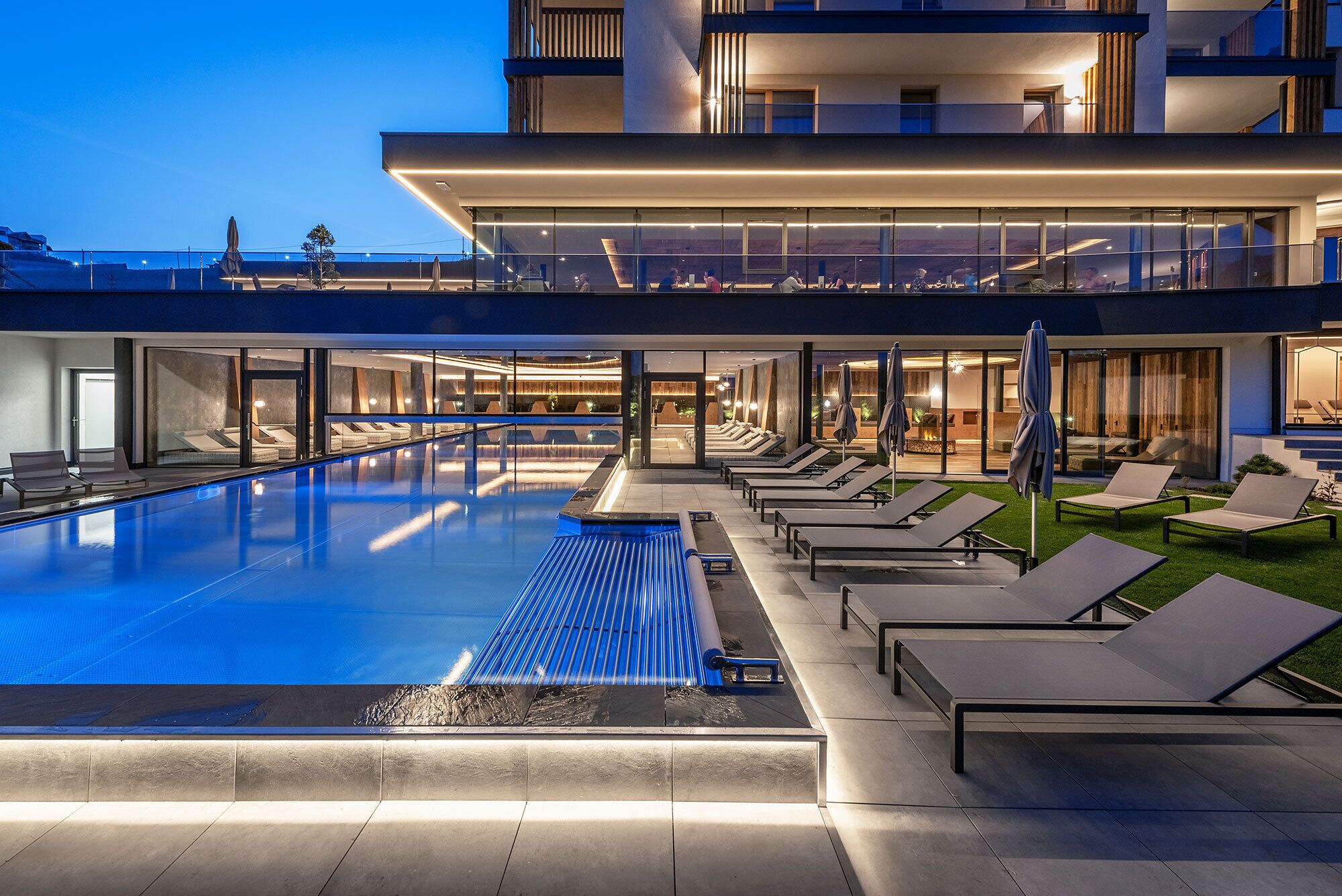 Una piscina techada, una piscina al aire libre, sombrillas