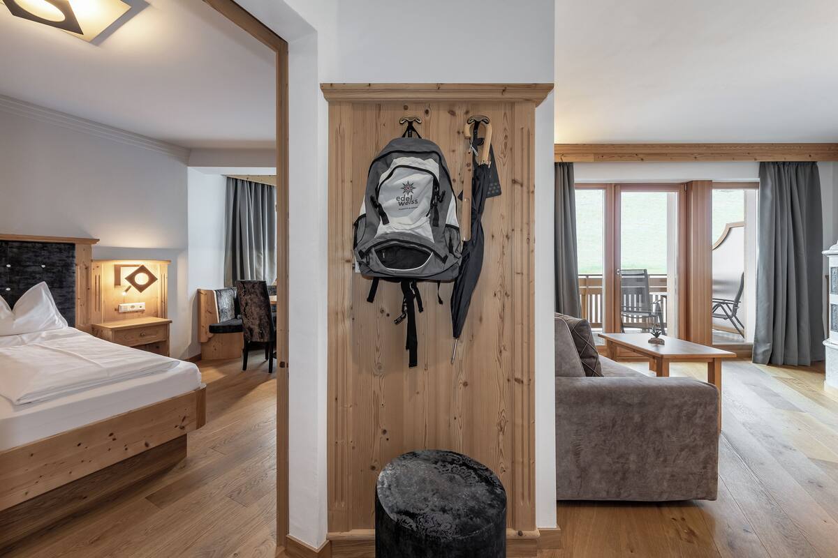 A hotel room with a bed, a wooden wardrobe, a seating area, and a view of the outdoors.