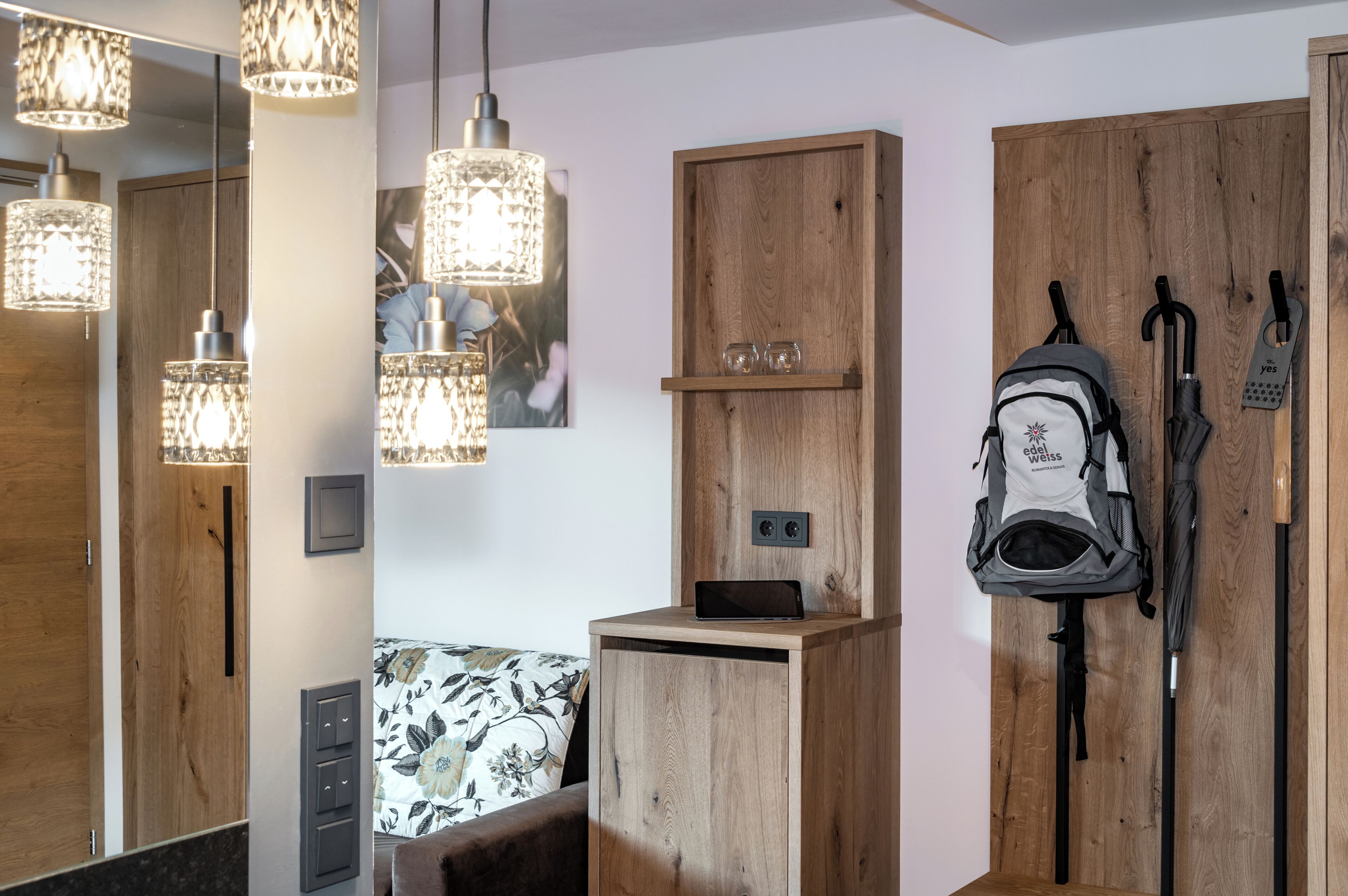 A room with wooden cabinets, a bench, a hanging backpack, and a wall-mounted umbrella.