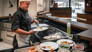 Un chef preparando un huevo en una plancha caliente en una cocina moderna, con diversos alimentos y condimentos sobre la encimera.