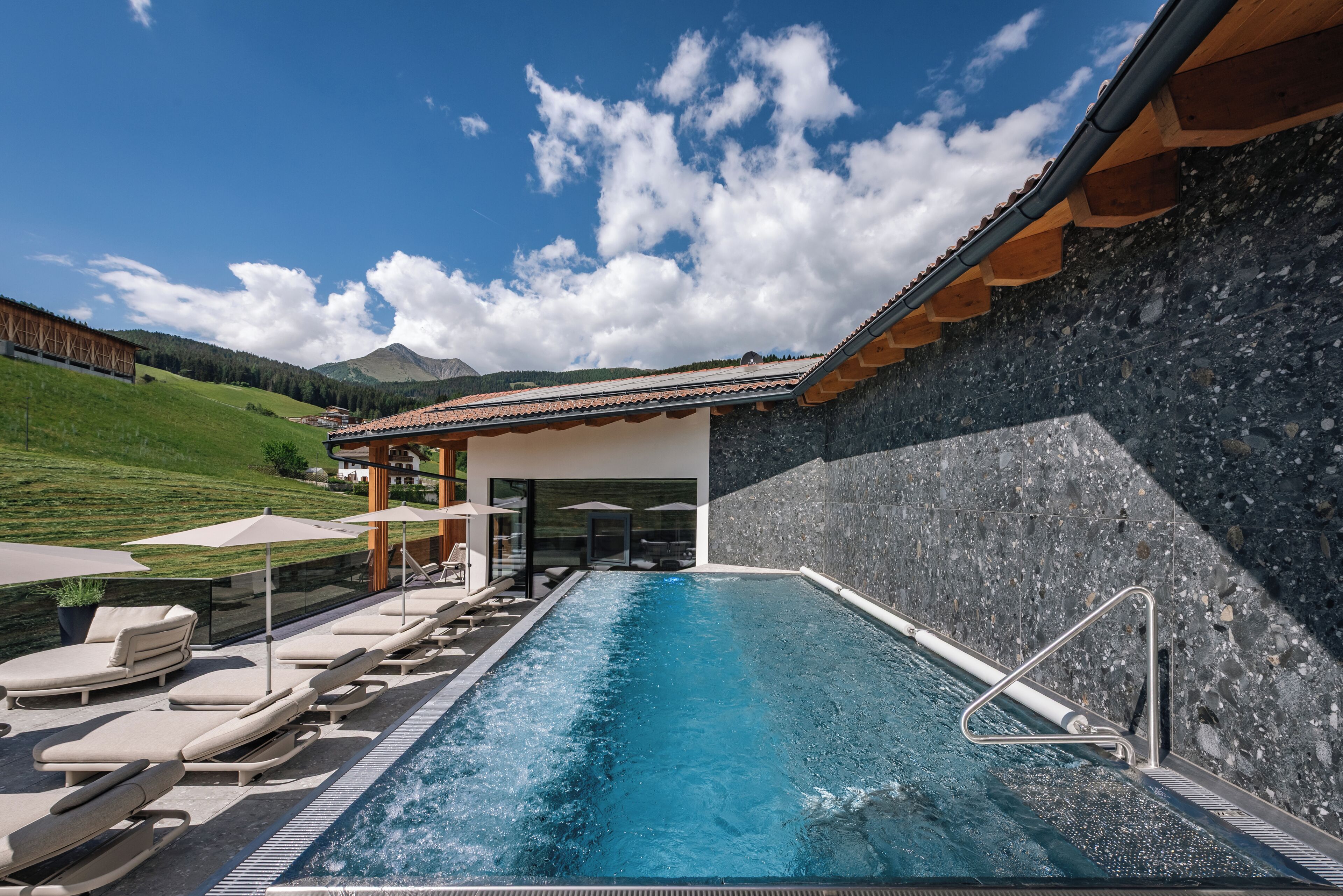 A pool area with lounge chairs, a clear blue pool, and a mountain backdrop.
