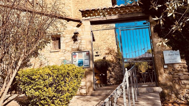 Un bâtiment en pierre avec une porte bleue, un escalier menant à l’entrée et une enseigne indiquant qu’il s’agit d’un hôtel.
