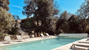Un espace piscine doté de chaises longues et d’un escalier menant à un mur en pierre.