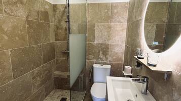 A modern bathroom with a glass-enclosed shower, a white sink, and a large mirror.