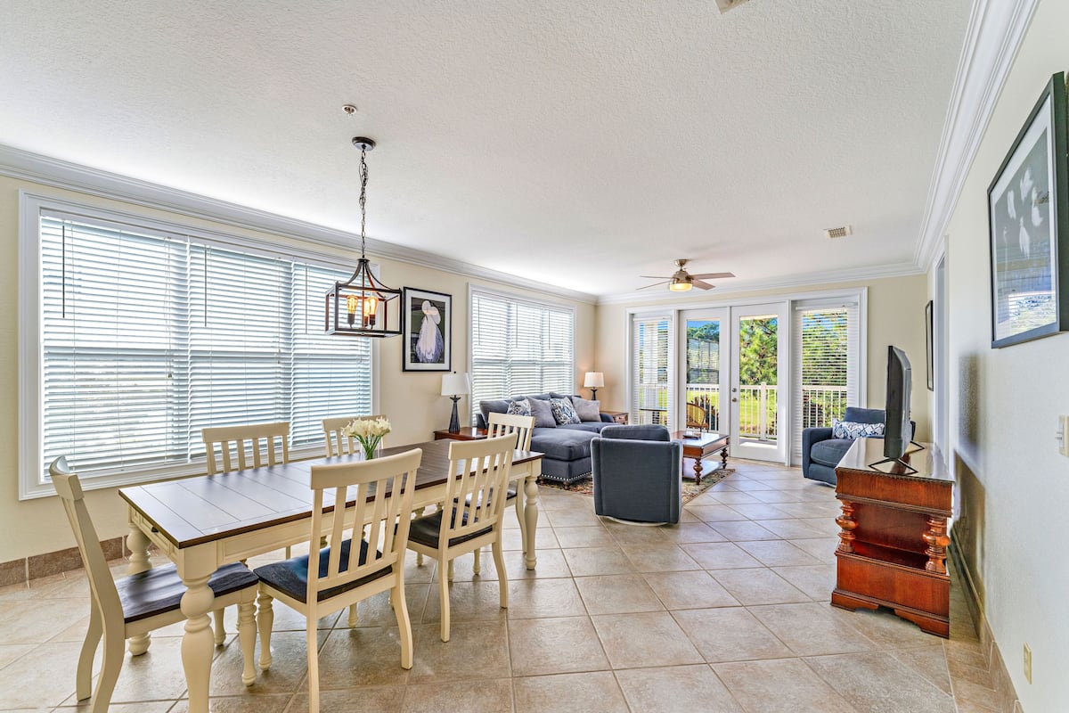 A spacious living area with a dining table, chairs, a sofa, and a television.