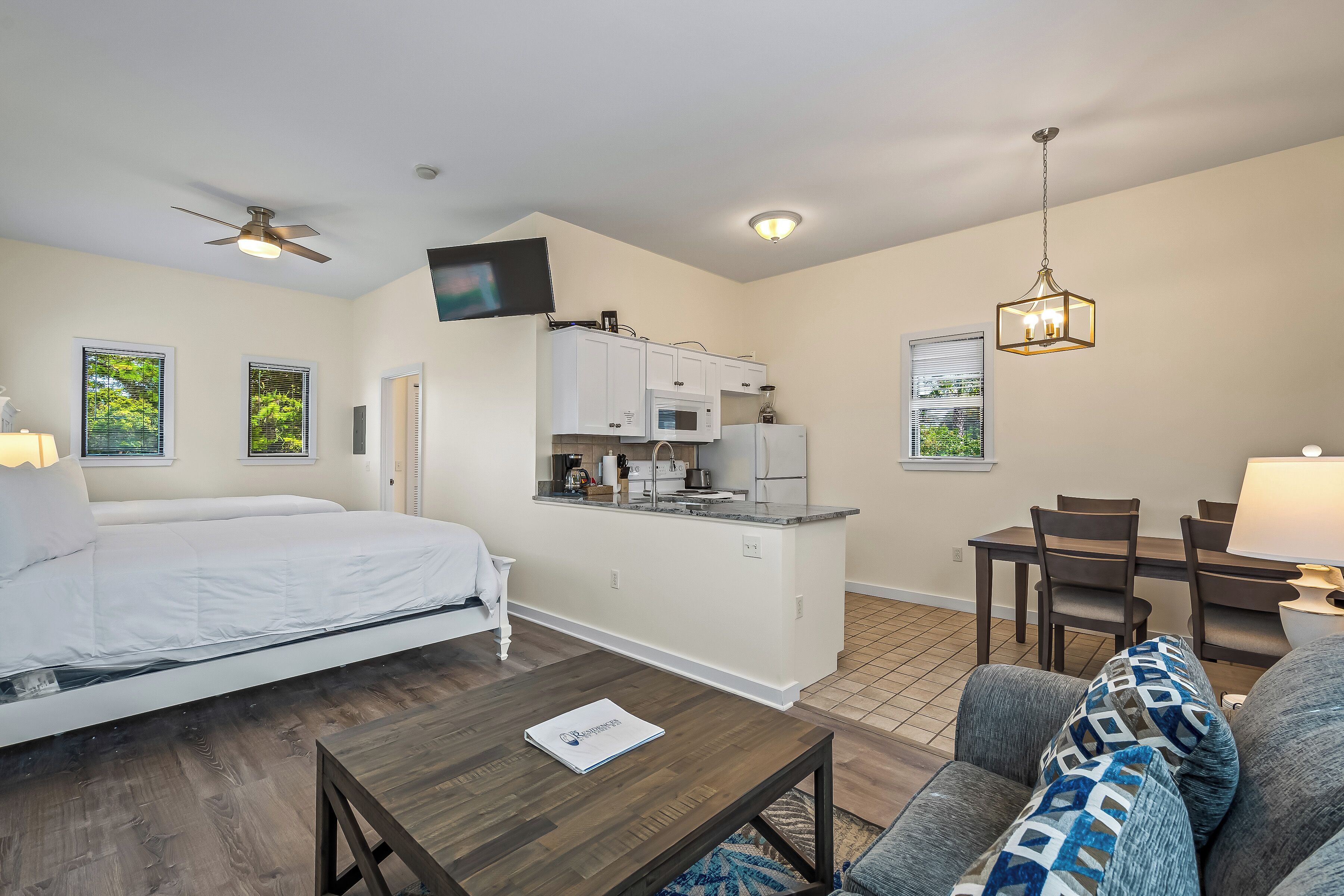 Un dormitorio con cama, una kitchenette pequeña, un área de comedor y una sala de estar con sofá.