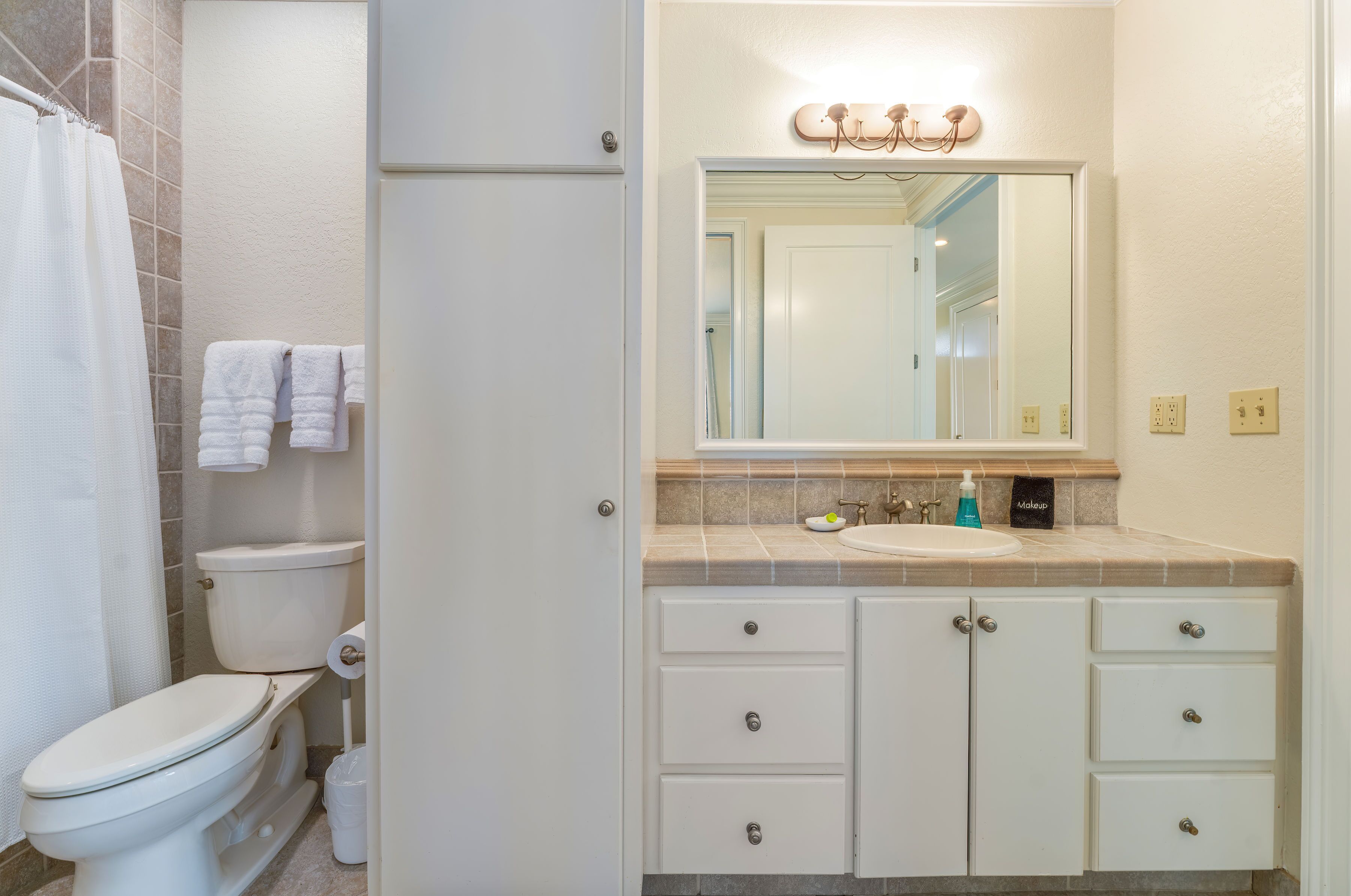 A bathroom with a toilet, sink, and mirror.