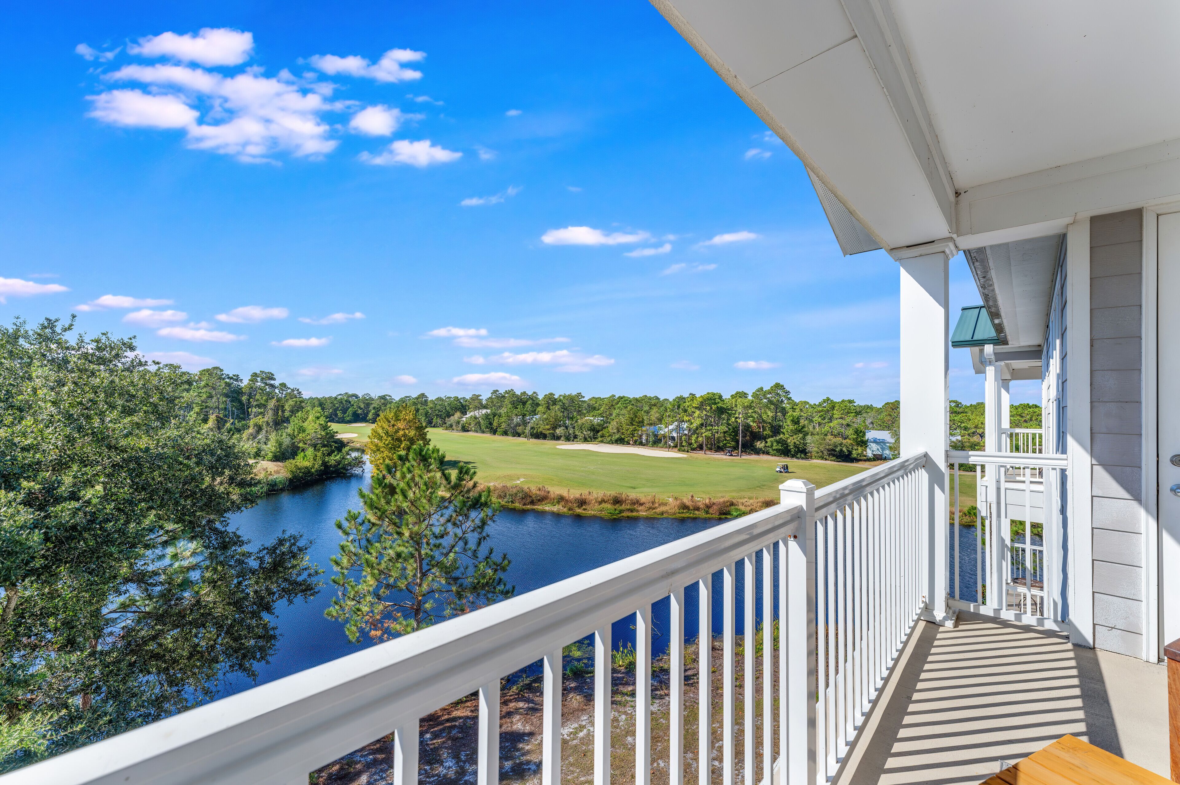A balcony with a view of a lake and a golf course.